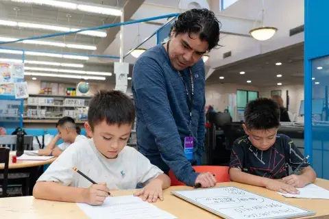 tutor and 2 youngs students in a library