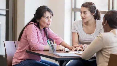 a mother and daughter consulting with an advisor across the table