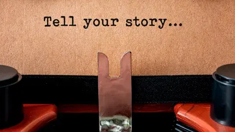 Sheet of paper in a typewriter reads "Tell your story"