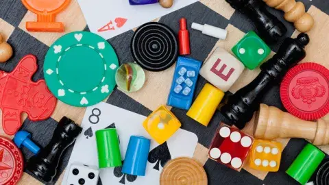 A variety of board game pieces, cards, and dice scattered on a chessboard.