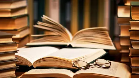 An open book among stacks.