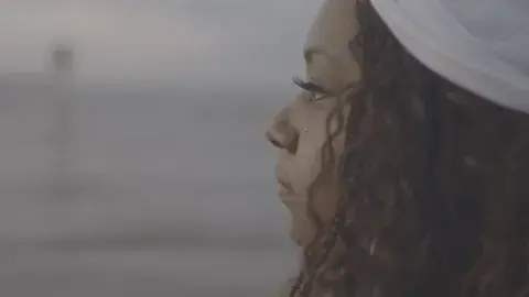 African american woman with a white headband stares out to sea