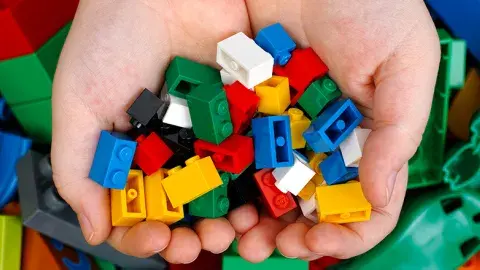 A child's hands holding toy building bricks.