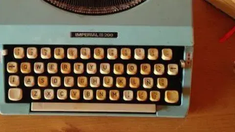 Typewriter and pen sit on a desk