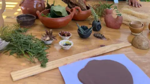 Clay is spread out on a table, along with dried flower petals and other textures that can be added to the clay