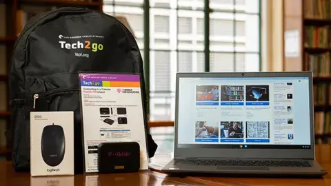 Items in a computer bundle including a Chromebook, a hotspot, a computer mouse, and a black backpack.